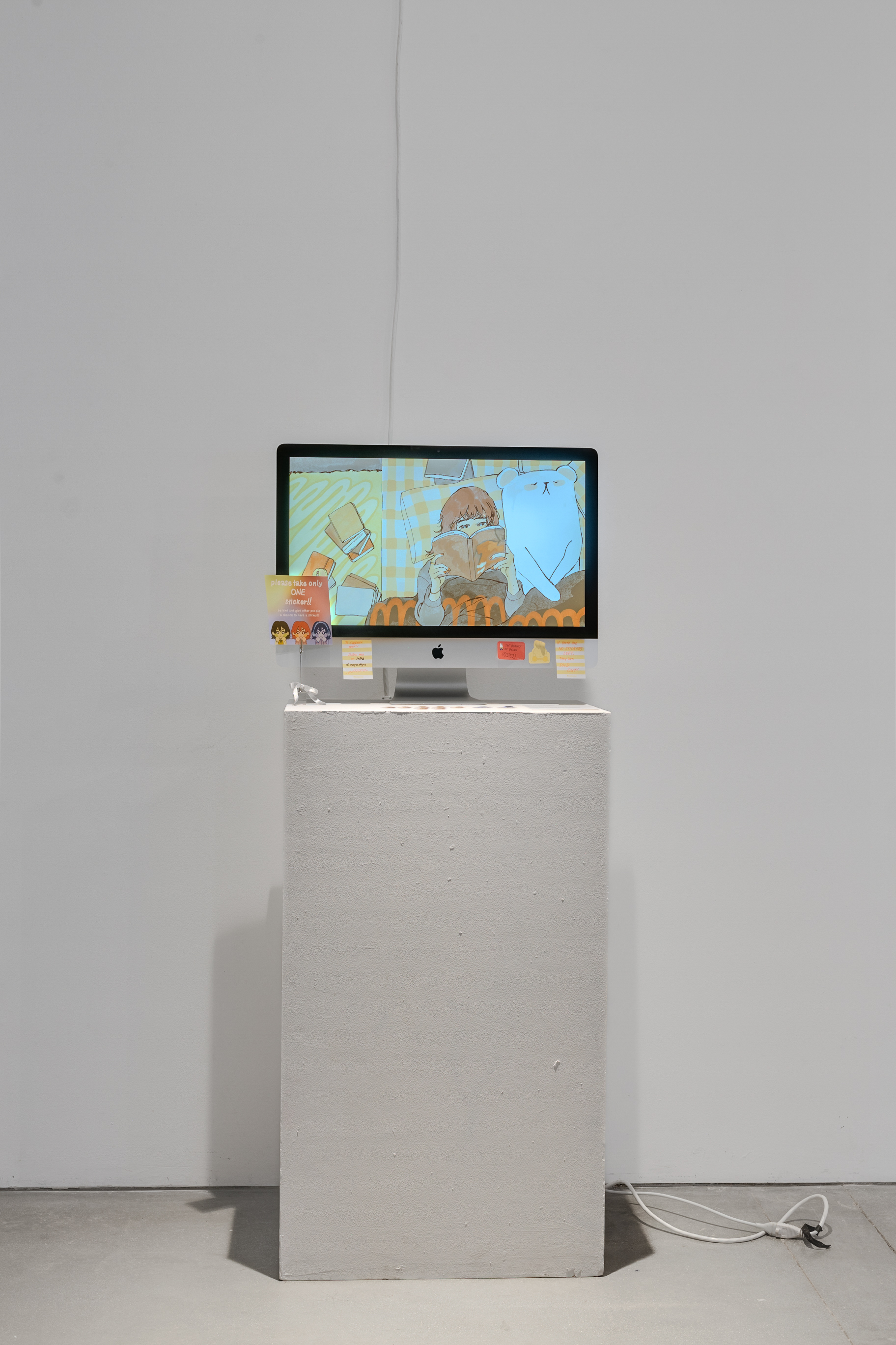 A computer monitor on a tall podium with illustrations displayed on it, against a plain white wall